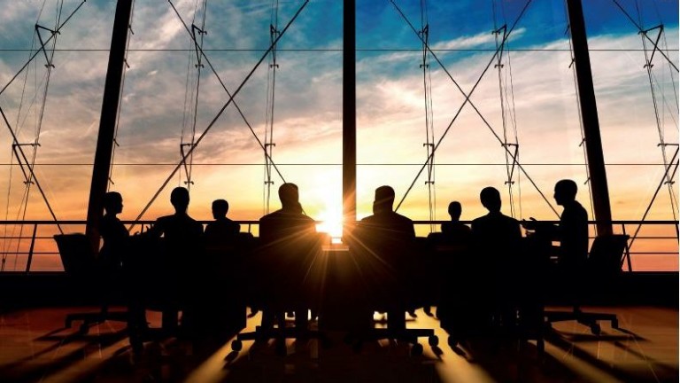 business leaders at conference table with windows and sunrise