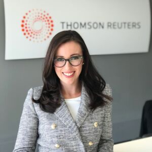 Tyrilly smiling while standing in front of the Thomson Reuters sign in our Australia office.