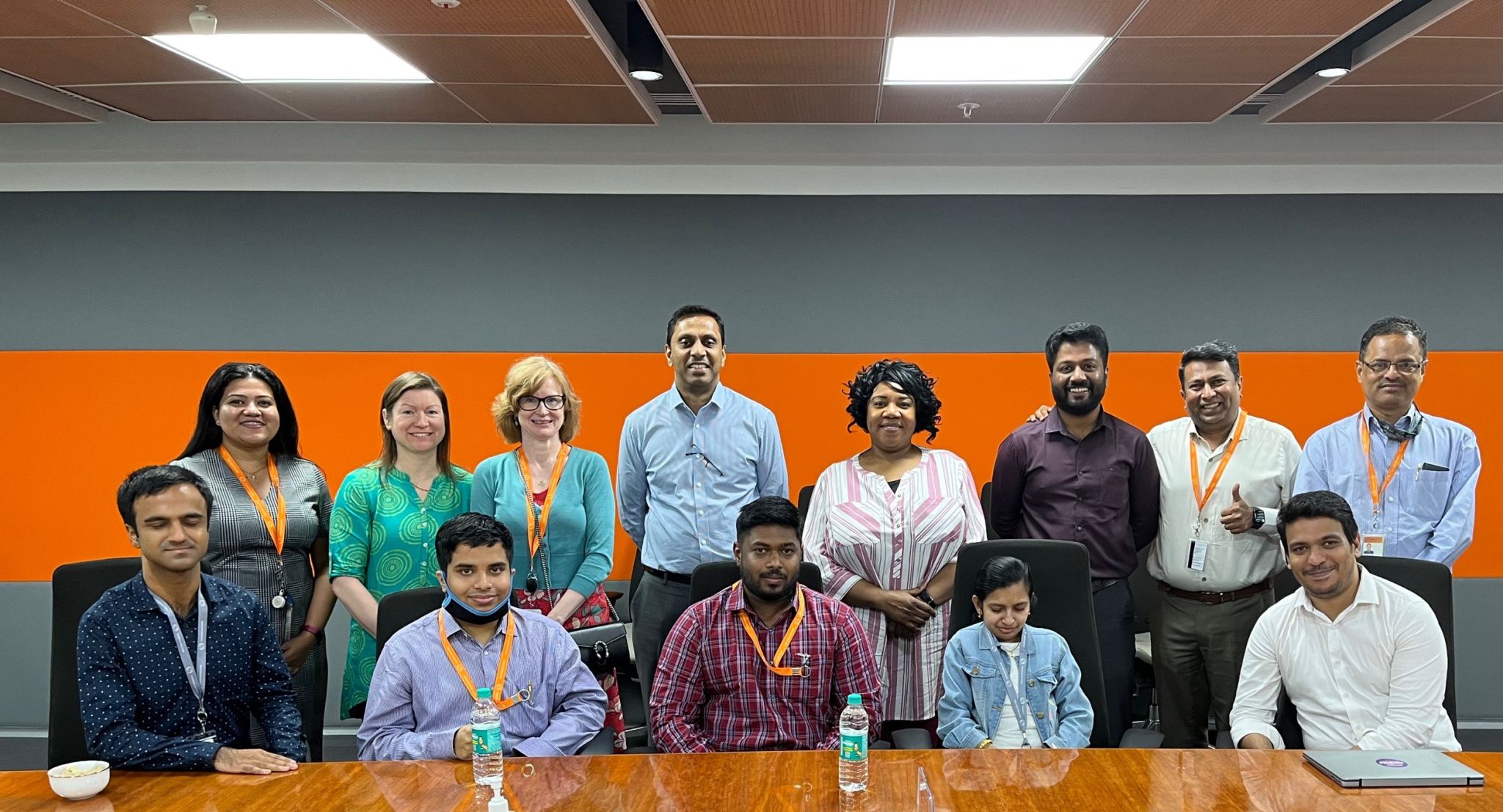 Participants in our Autism Spectrum internship sitting at a table in our India office posing for a group photo with several leaders.