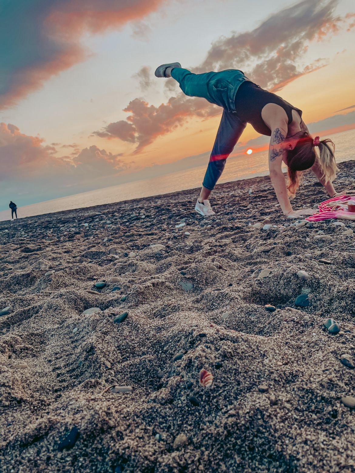 Agata doing a handstand on the beach as the sun is setting in the background