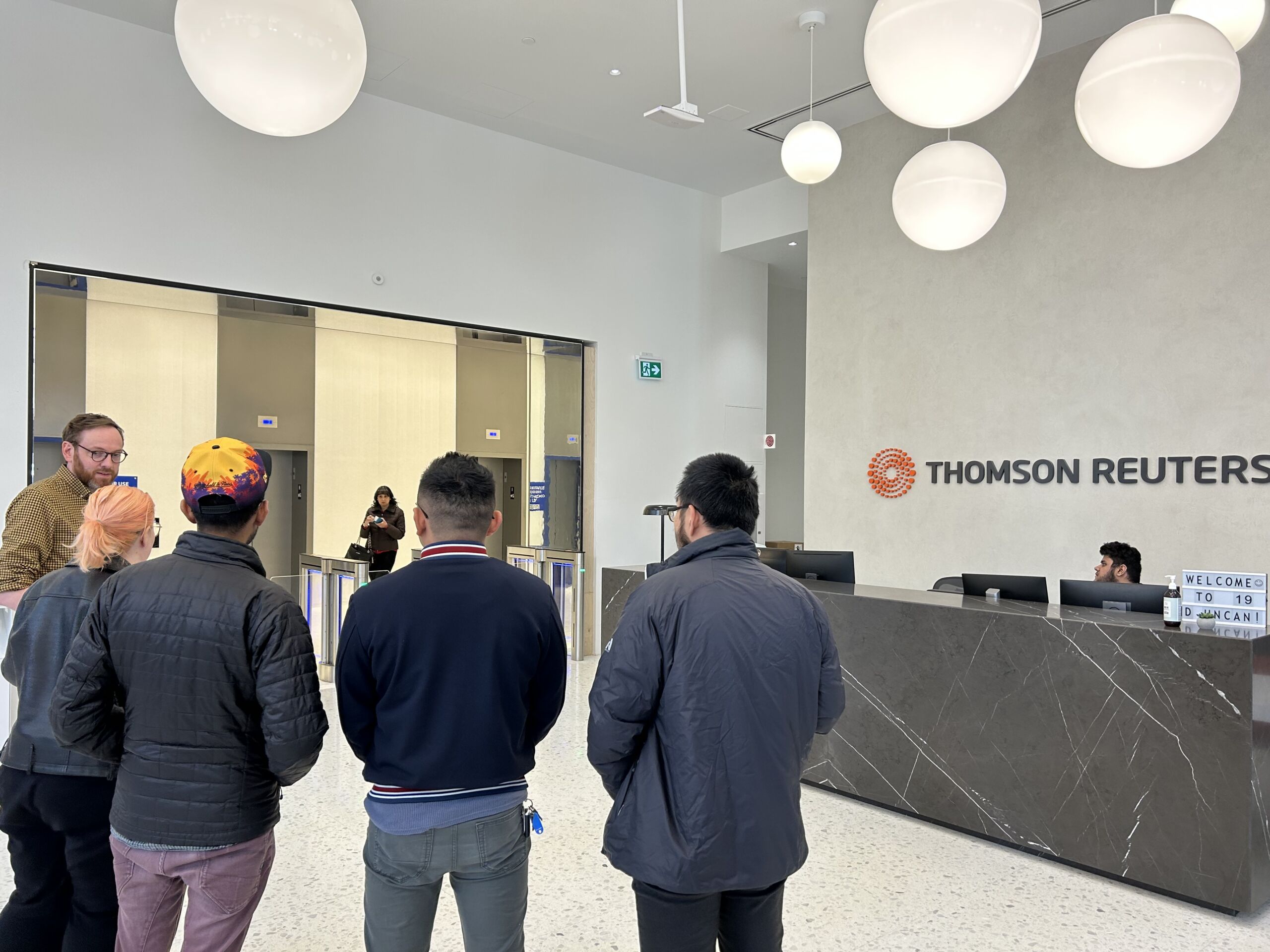 Teammates in Toronto standing in the lobby while touring the new center, examining the accessibility features, and learning about Thomson Reuters' inclusive workplace design guidelines.