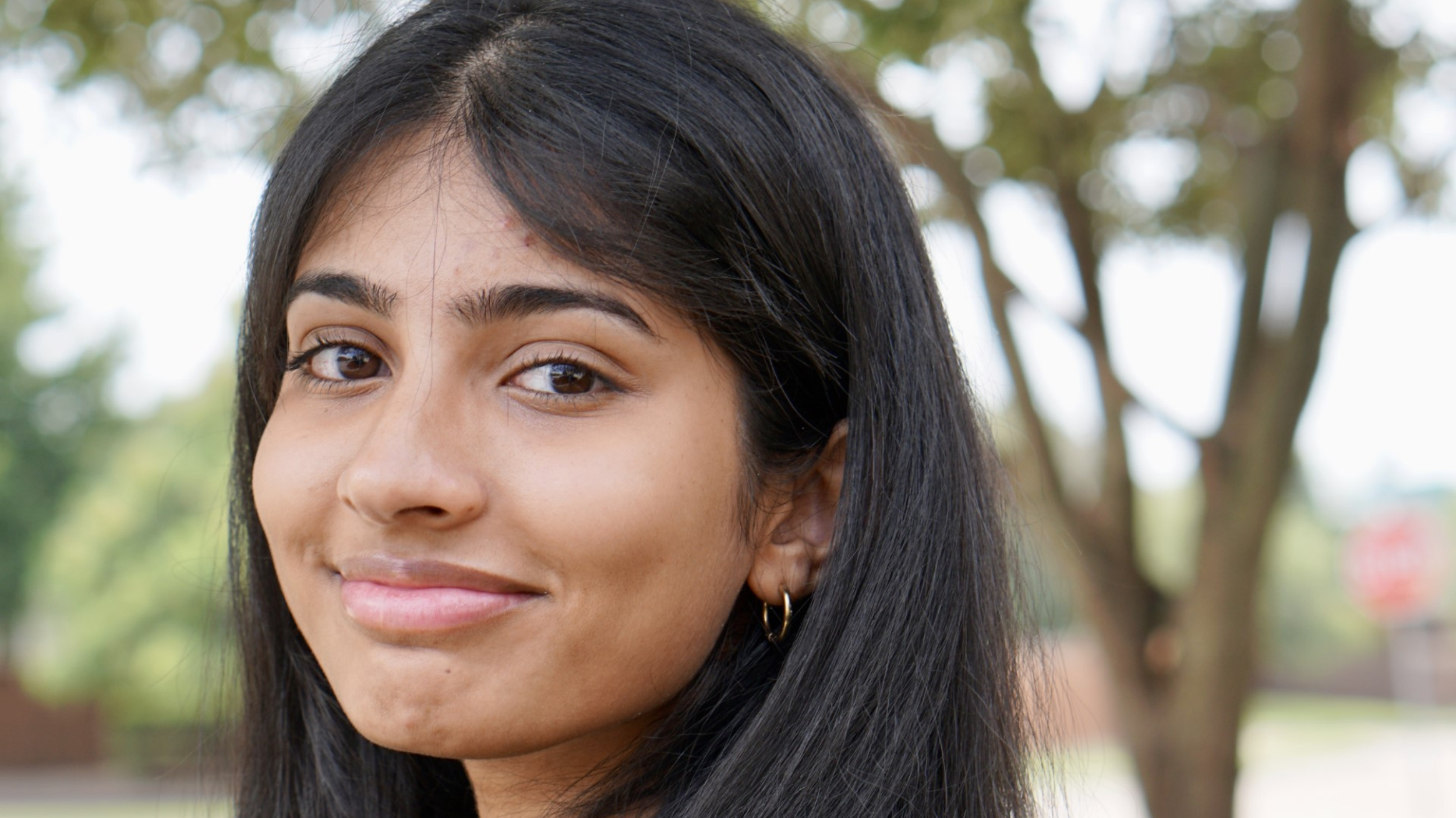 Sneha, a software engineering intern, facing away from the camera and smiling while wearing a black shirt.