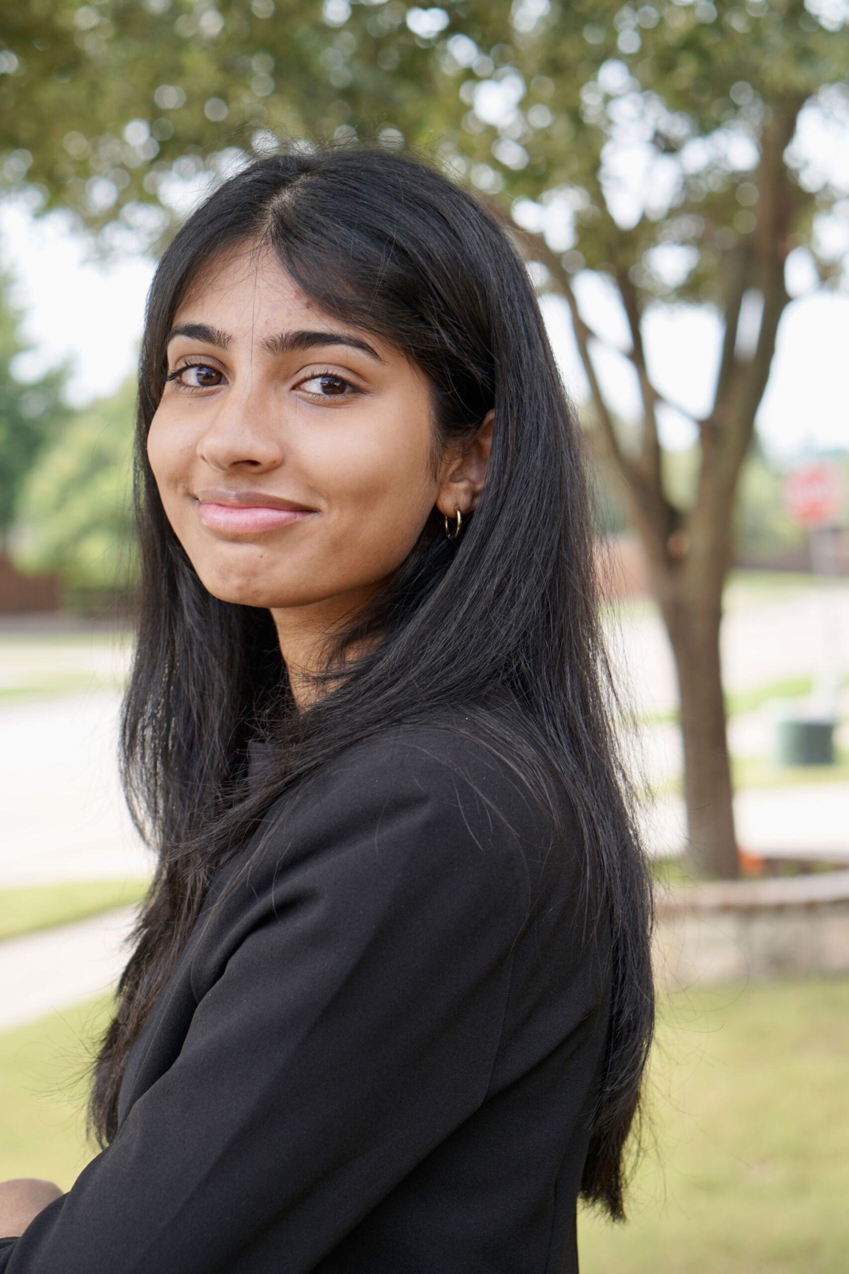 Sneha facing away from the camera and smiling while wearing a black shirt.