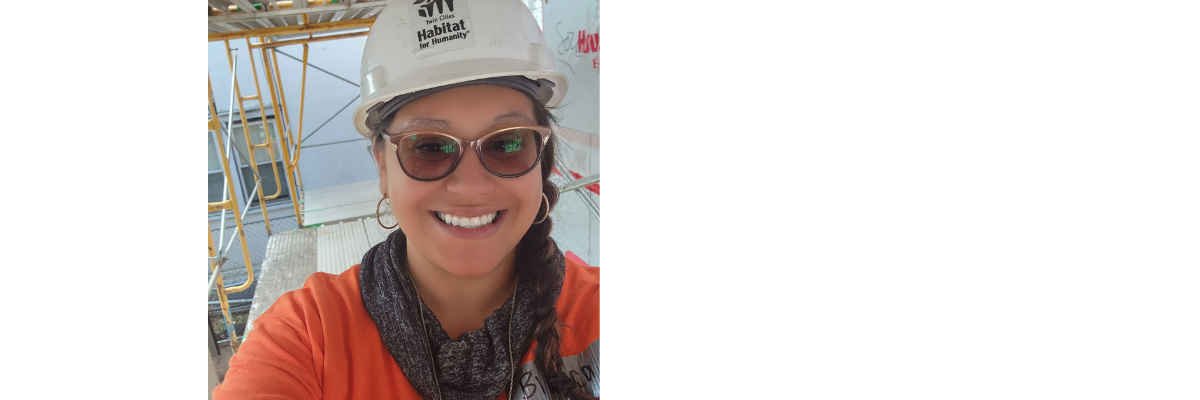 Bianca smiling and taking a selfie while wearing sunglasses and a construction hat.