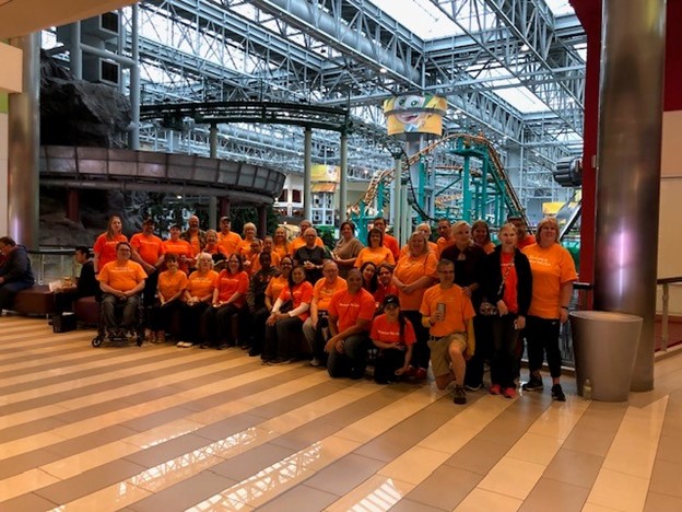 A large group of people pose for a picture together inside the Mall of America. 