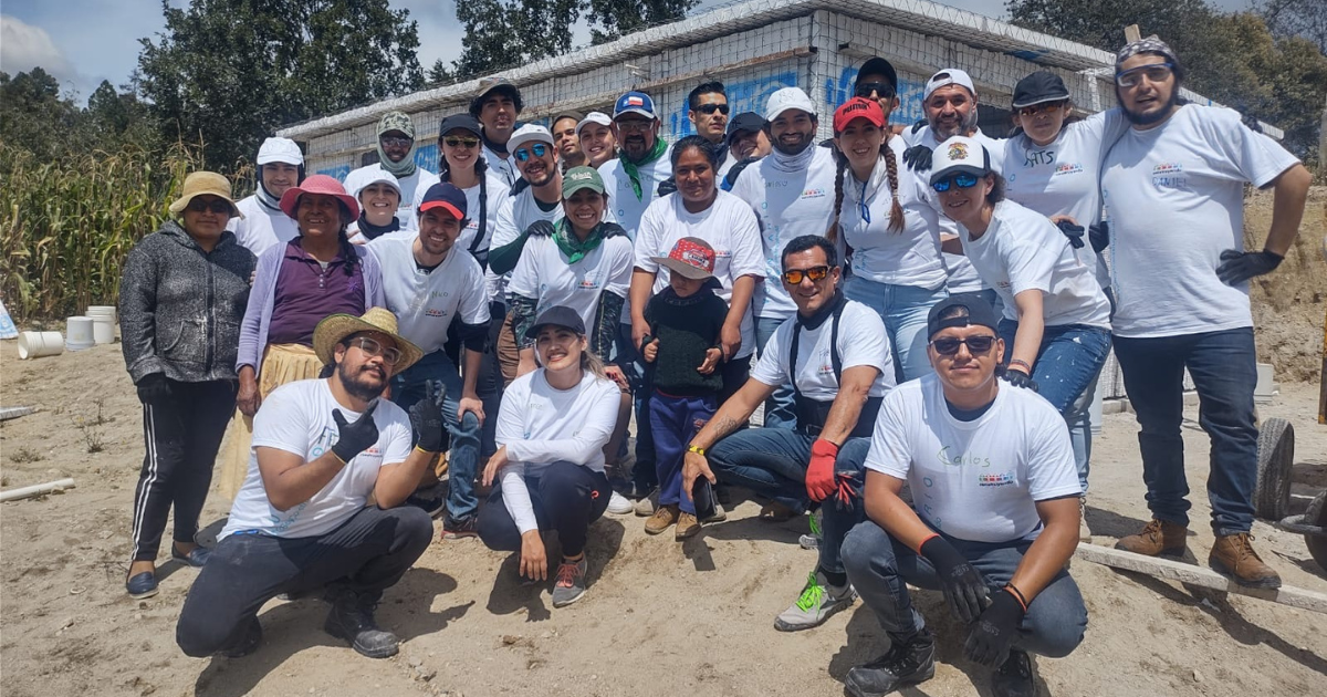 A large group of teammates in Mexico pose for a photo in front of the home they helped construct.